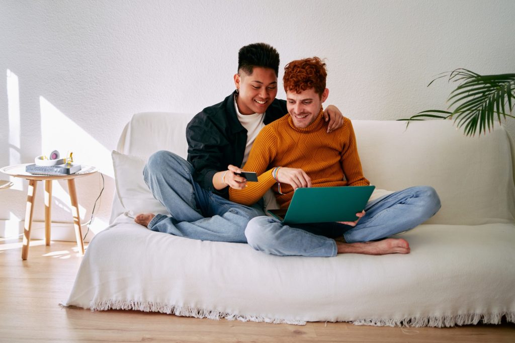 Happy gay couple using a card to shopping online