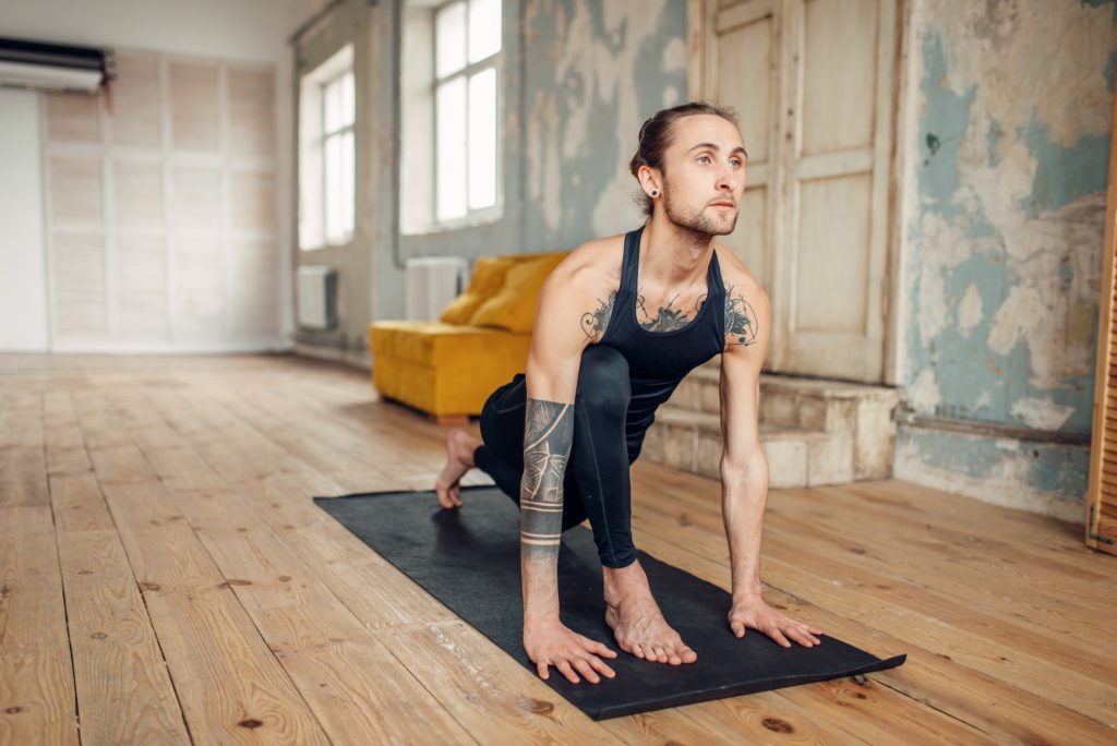 Male yoga with tattoo on hand doing exercise